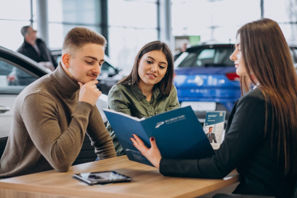 Young couple talking to a sales person in a car showroom